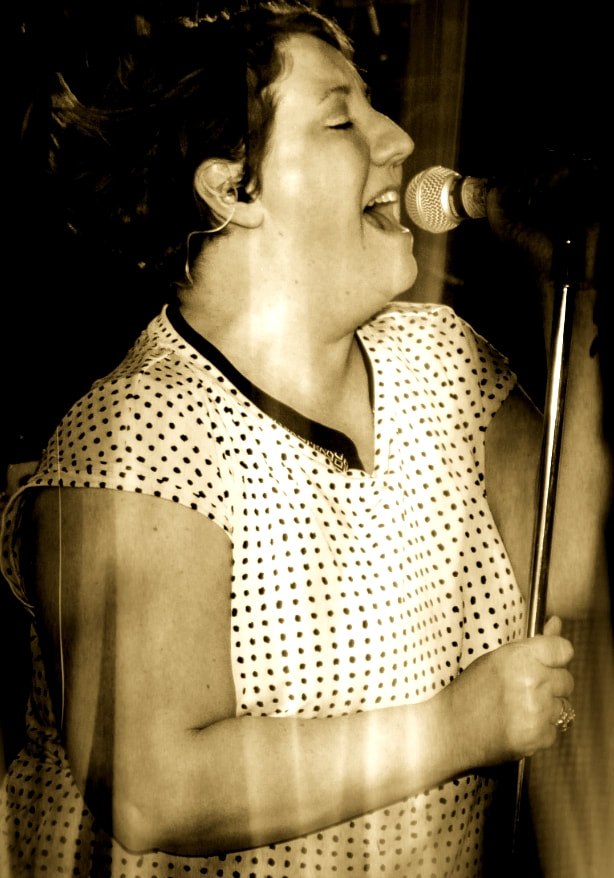 a female singer with short hair belts out a song into a microphone